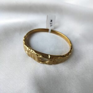 Close-up of gold-plated sculpted cuff bracelet with abstract design