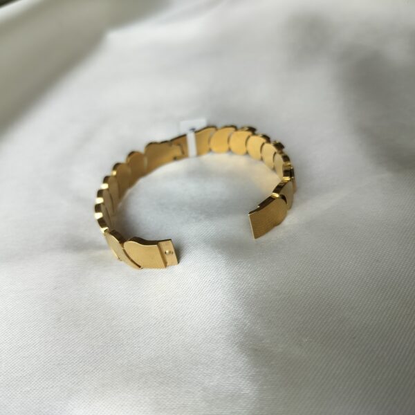 Macro shot of hinge clasp mechanism on the gold oval bracelet, showing smooth operation and secure closure