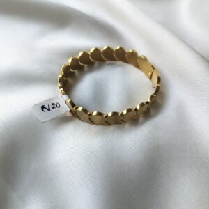 Golden comma-link bracelet with oval cuff and hinge clasp, showing anti-tarnish gold finish