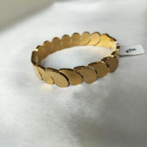 Close-up of oval gold bracelet showing alternating textured and smooth comma-links with visible hinge clasp