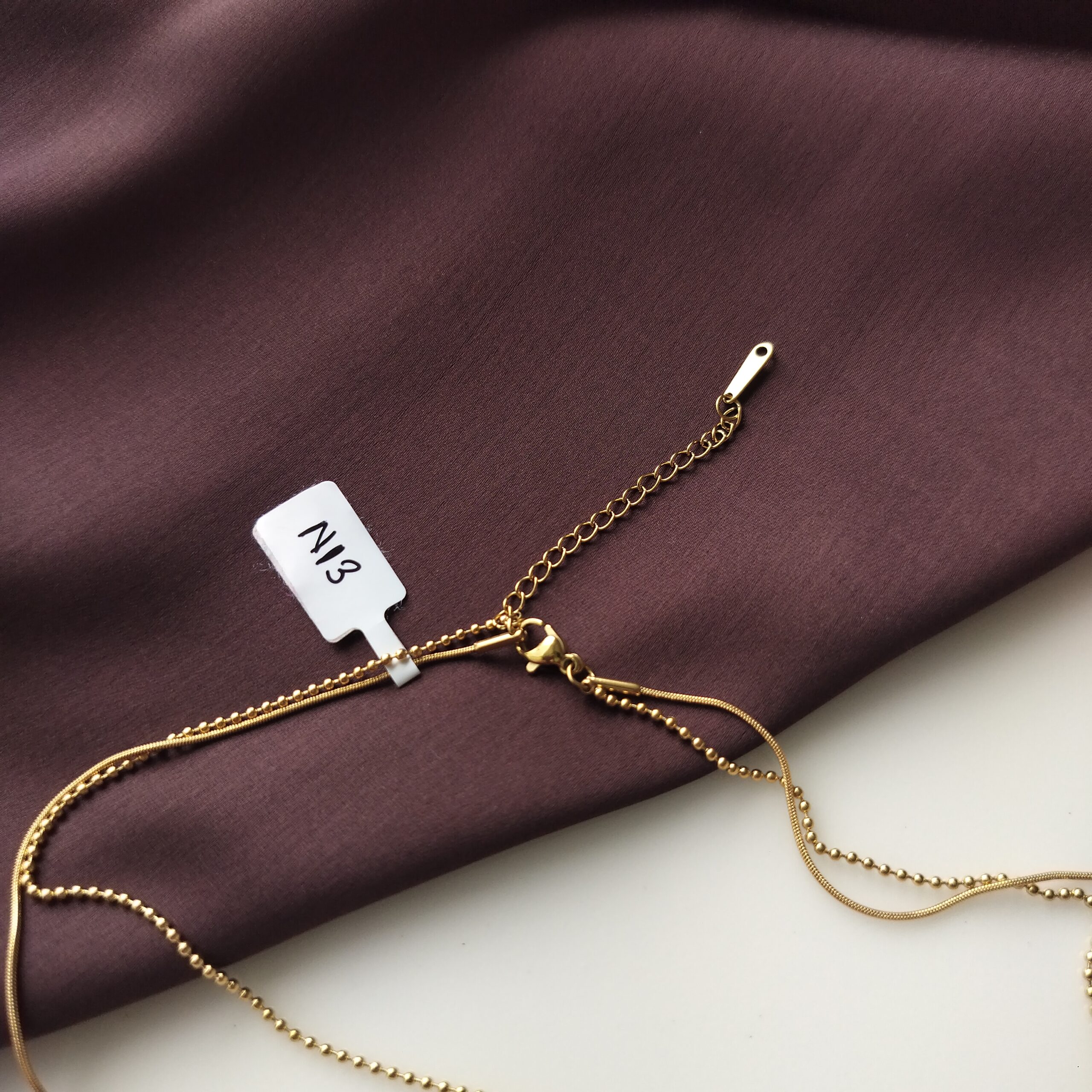 Person adjusting the extra chain on the Amber Luxe necklace.