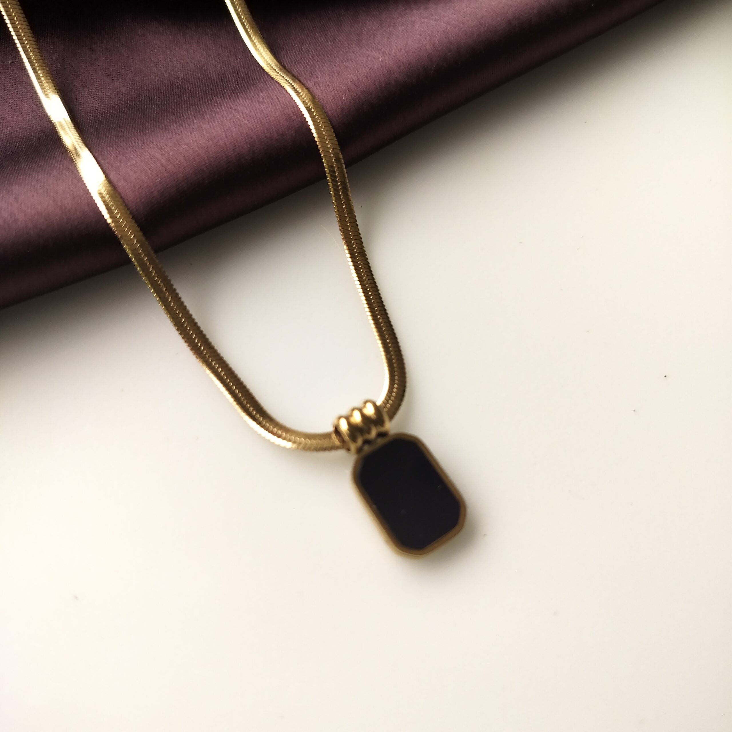 Close up detail of the polished black obsidian stone in gold setting.