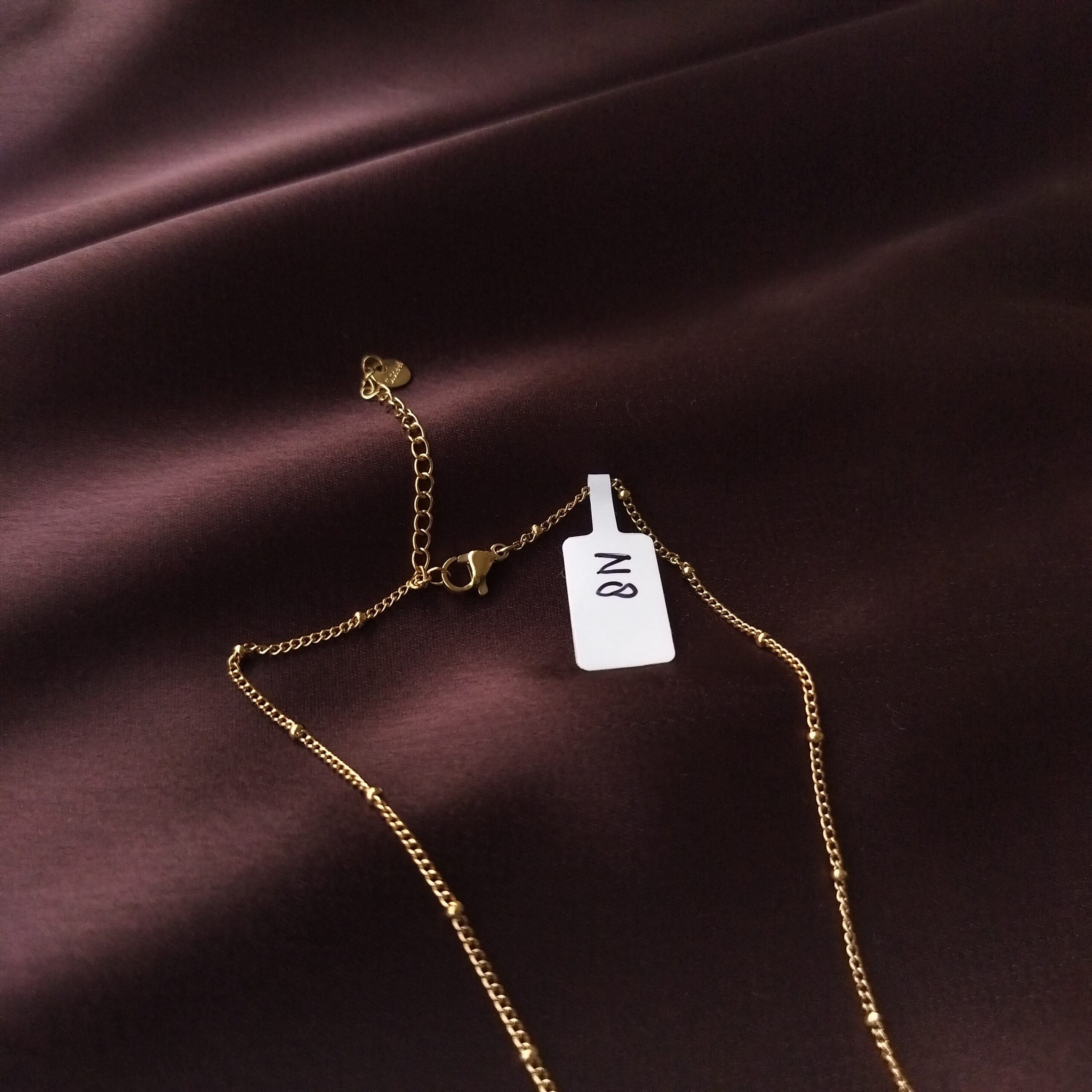 Woman adjusting the extra chain on the Golden Heart Necklace.