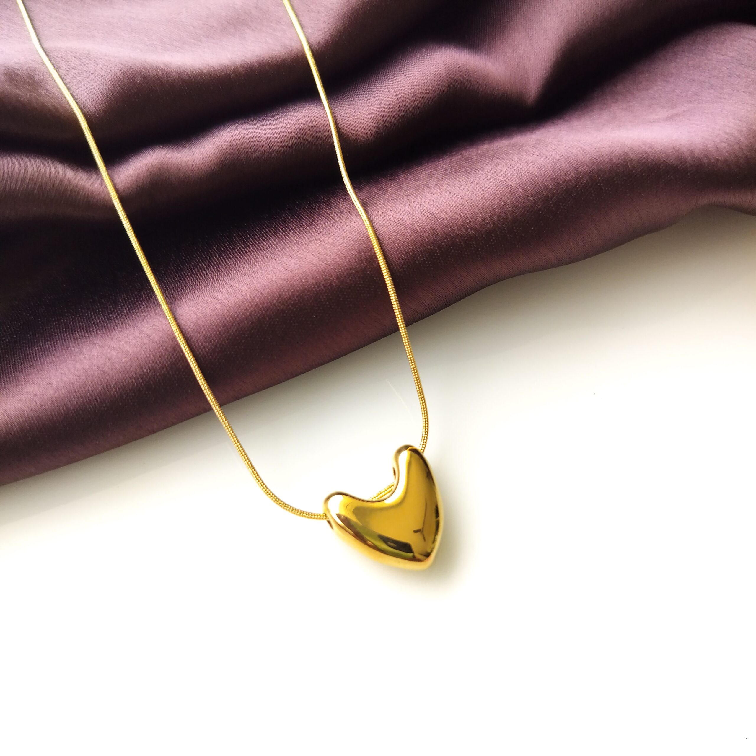 Close up of the smooth gold plated heart pendant